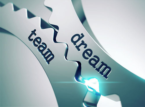 Close up of two gears meshing: one reads Dream, the other reads Team